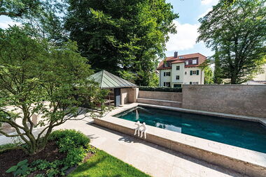 Ein Swimming-Pool aus Beton in einer Gartenanlage.
